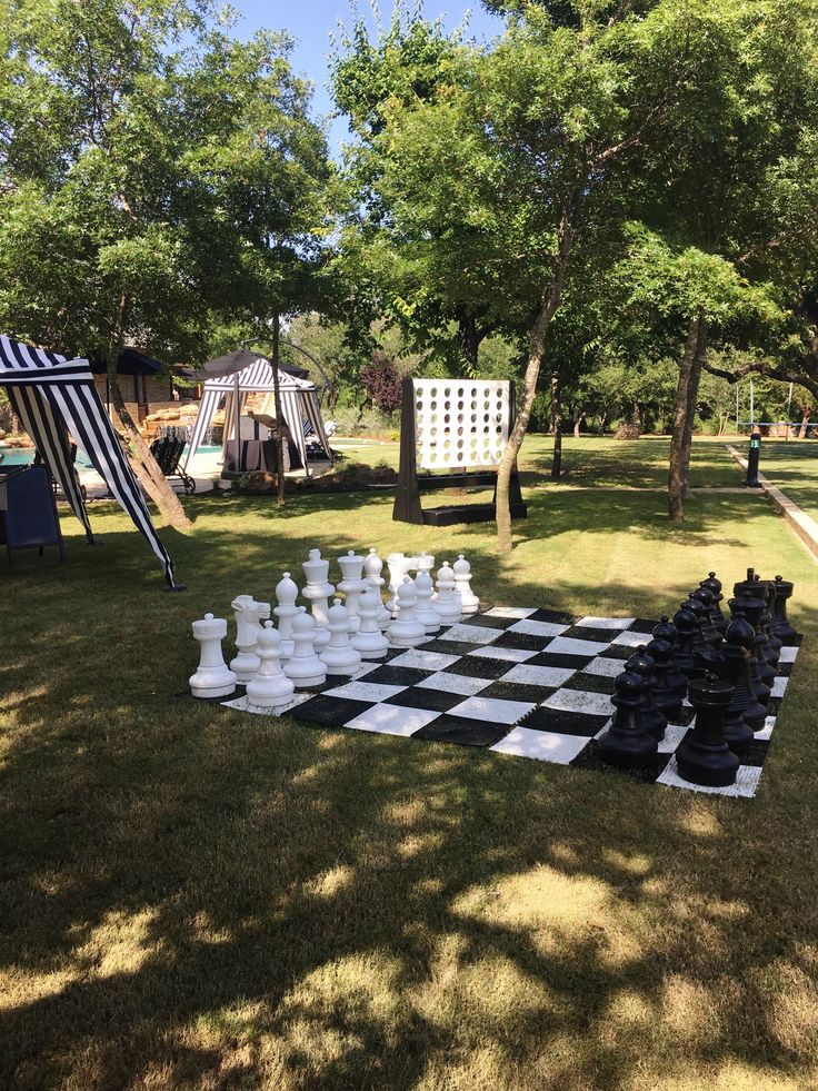 a giant chess set up in the grass next to a tent and picnic table with chairs