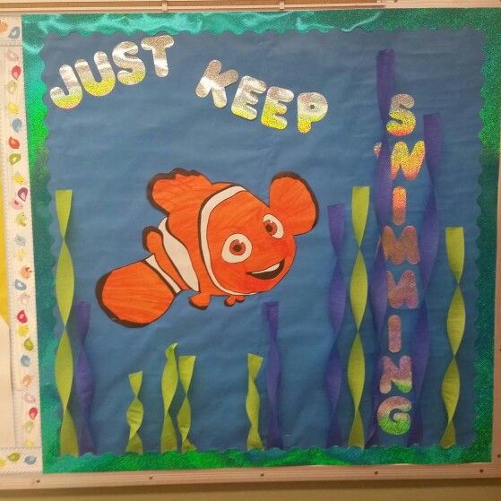 a bulletin board with an image of clown fish and words just keep swimming on it