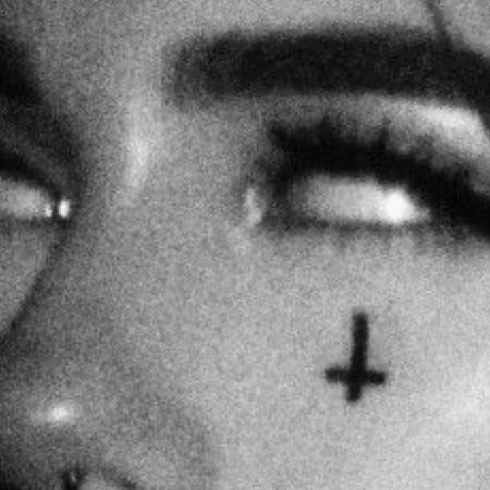 a woman with a cross tattoo on her nose and eyeliner is looking at the camera