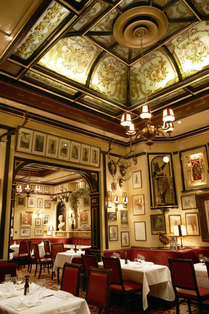 a dining room with tables and chandeliers on the ceiling is decorated in gold, white and red