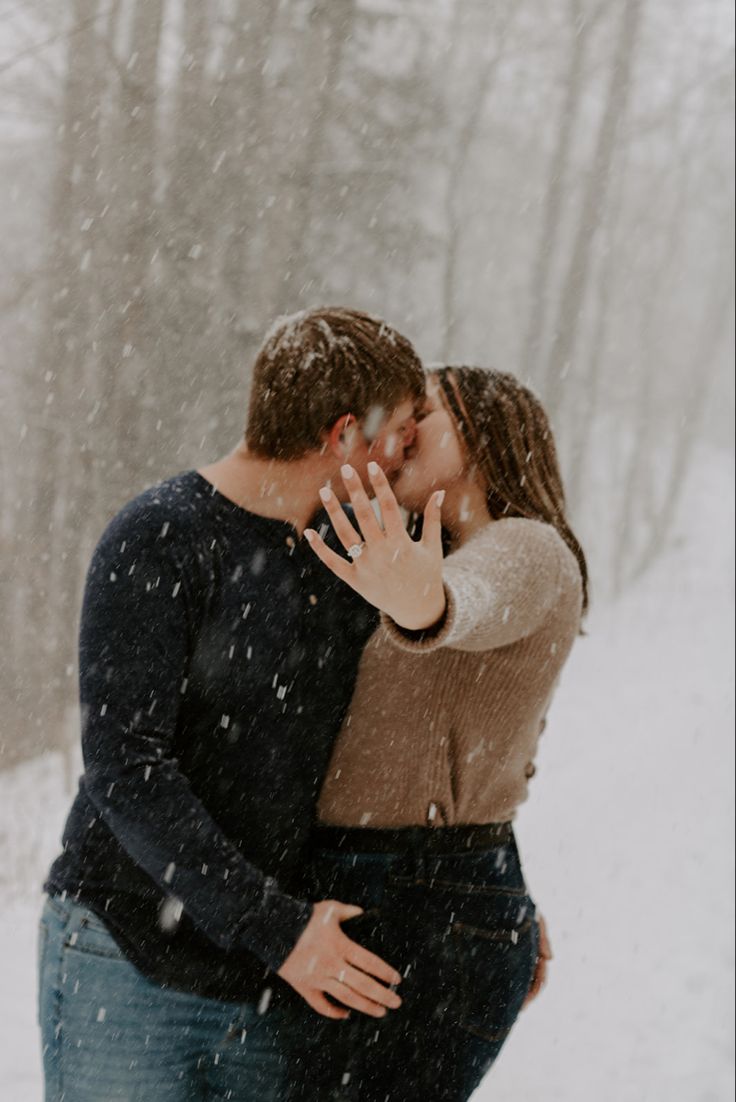 a man and woman kissing in the snow with their hands on each other's face