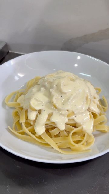 a white plate topped with pasta covered in gravy on top of a table