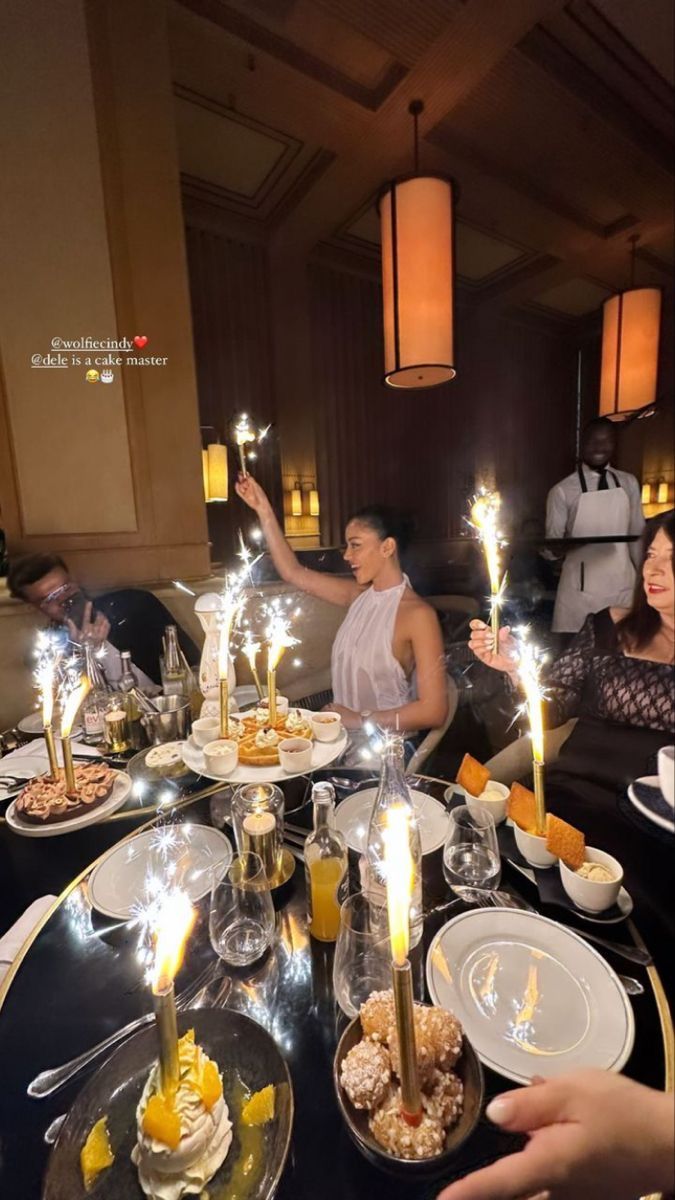 people sitting at a table with candles in their hands and food on the plates around them