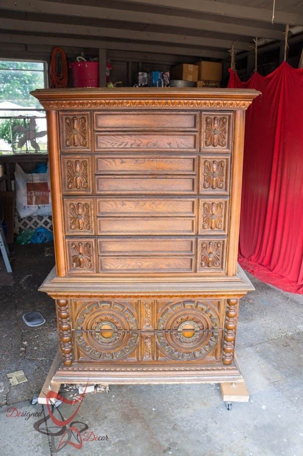 an old wooden cabinet with carvings on the front and sides, sitting in a garage