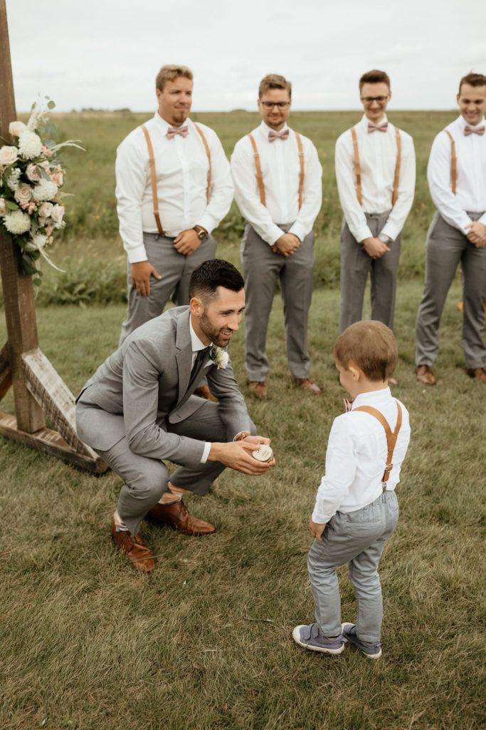 a man kneeling down next to a little boy in front of some other men wearing ties