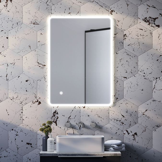 a bathroom sink with a mirror above it and a light on the wall behind it