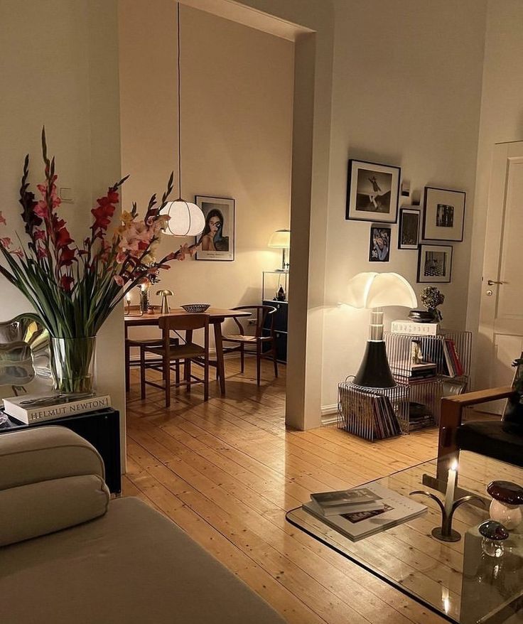 a living room filled with furniture next to a dining room table and chairs on top of a hard wood floor