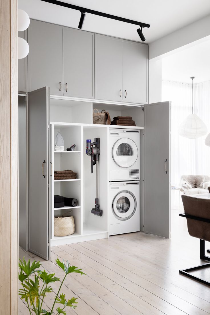 a washer and dryer in a room with white walls, wooden floors and cabinets