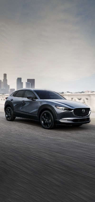 the new mazda cx - hr is driving on a road in front of a cityscape