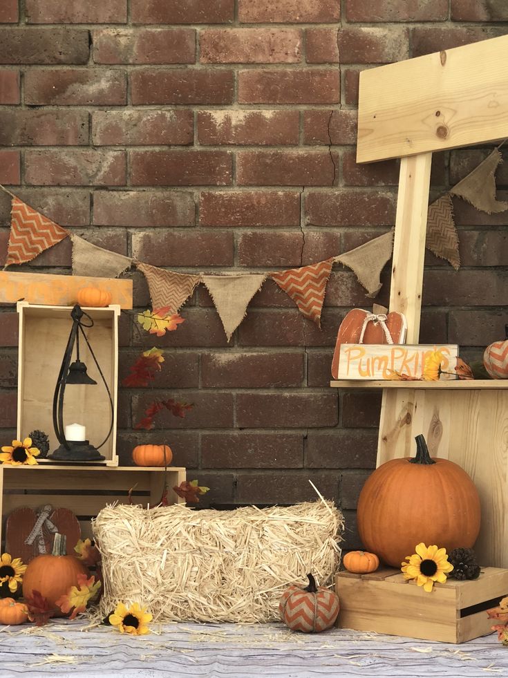 pumpkins, hay and sunflowers are on display in front of a brick wall