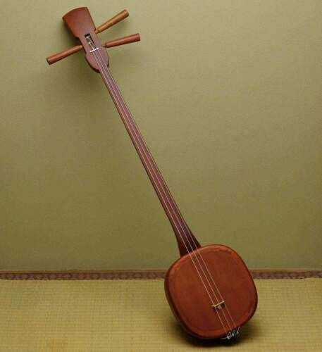 a small wooden instrument sitting on top of a floor next to a wall with two sticks sticking out of it