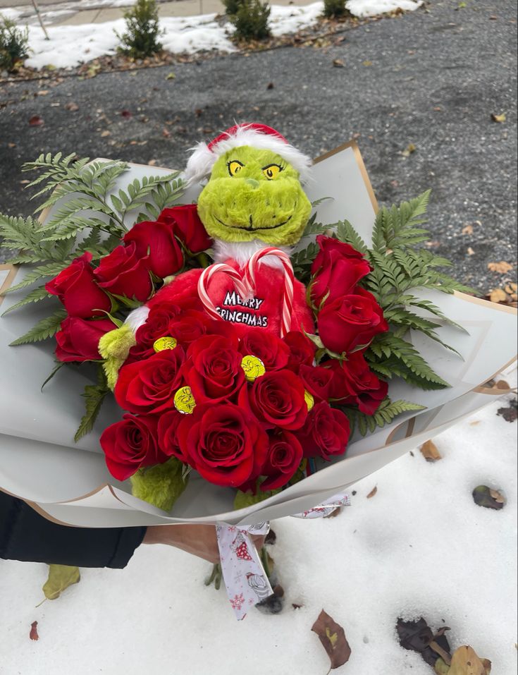 a bouquet of roses and a stuffed animal in the snow