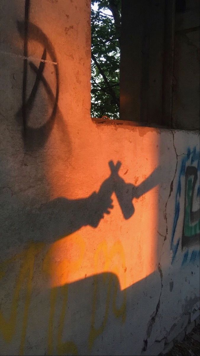 the shadow of a person's hand on a wall next to a street sign