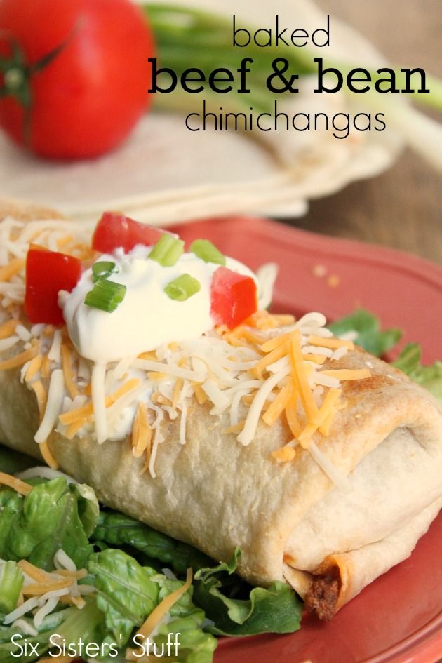 a burrito on a plate with lettuce, tomatoes and sour cream cheese