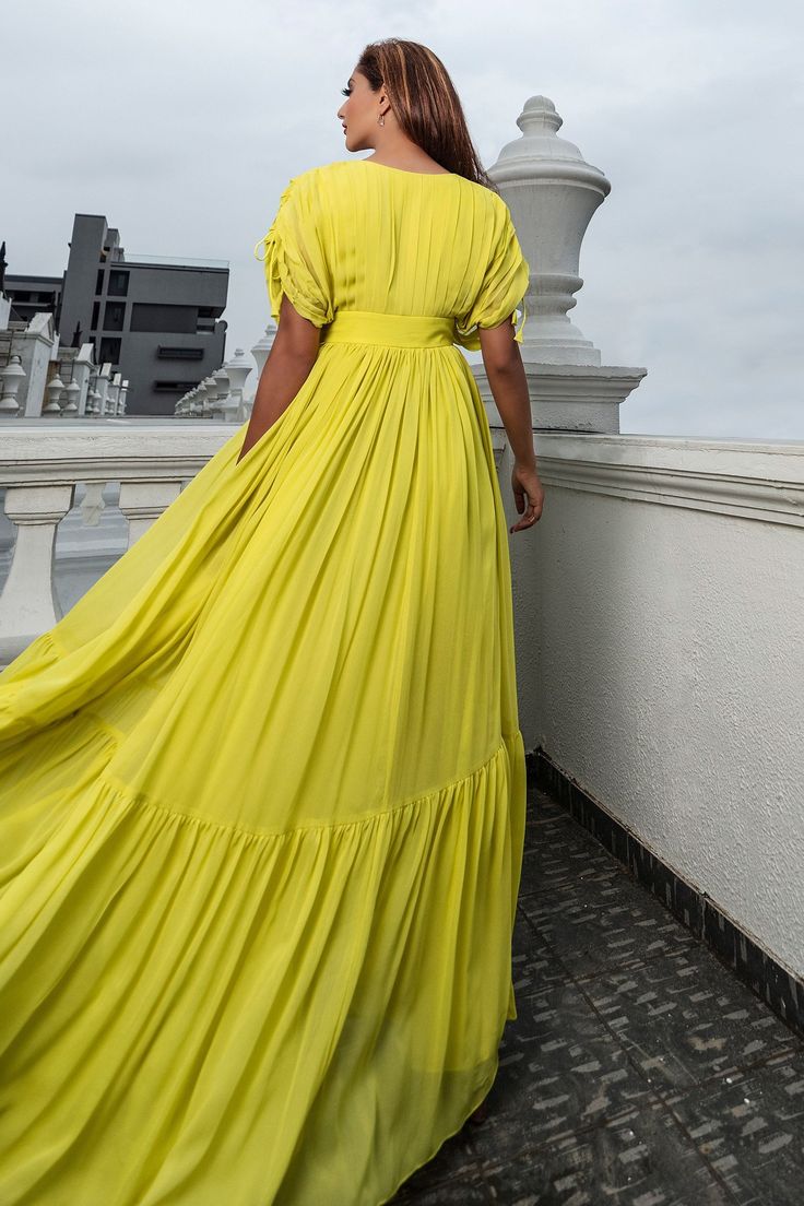 Lemon yellow gown in georgette base with draped front and sleeves .
Component: 1
Pattern: Plain
Neckline: V-neck
Sleeve Type: Draped Sleeves
Fabric: Georgette
Color: Yellow
Other Details: 
Draped sleeves with drawstring tie-up
Tiered gown
Occasion: Cocktail - Aza Fashions Gown Yellow, Tiered Gown, Cape Jumpsuit, Draped Gown, Yellow Gown, Draped Sleeves, Drape Gowns, Gown For Women, Drape Sleeves