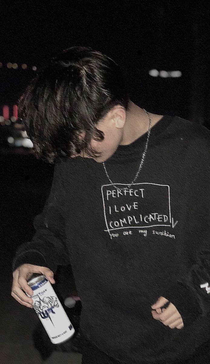 a young man is holding a can of beer in his hand and looking down at the ground