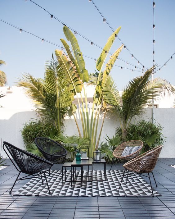 two chairs and a table on a tiled patio with potted plants in the background