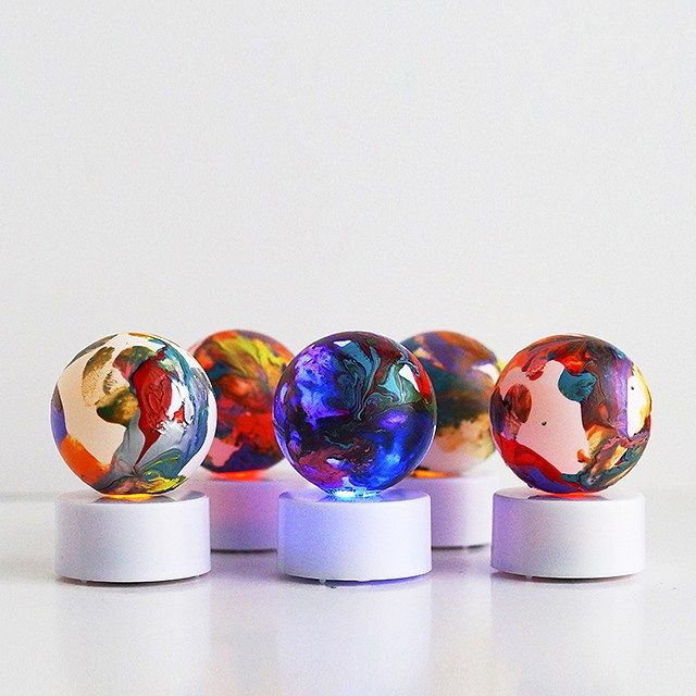 four glass marbles sitting on top of white bases