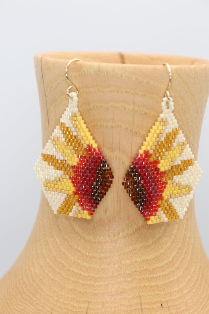 a pair of beaded earrings sitting on top of a mannequin dummyine