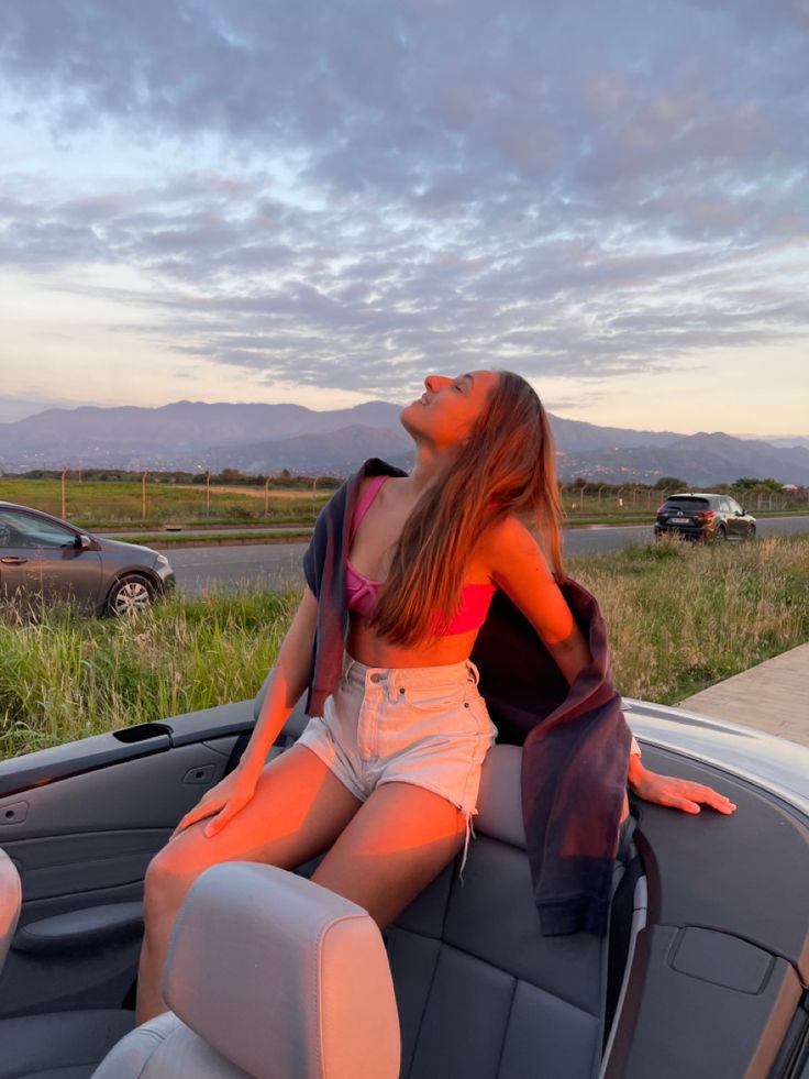 a woman sitting on the back of a car