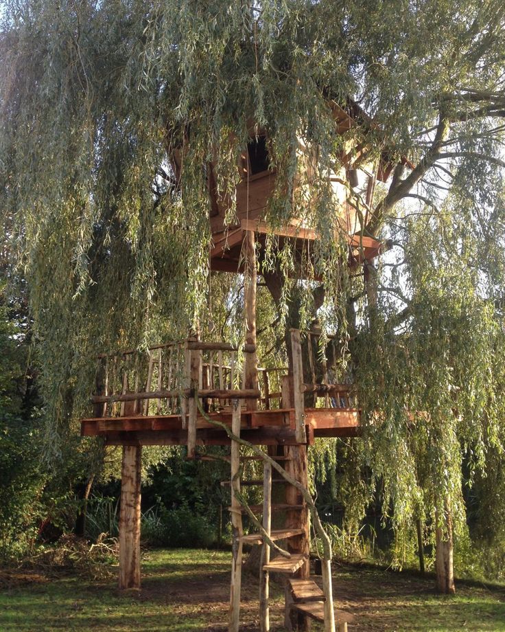 a tree house built in the middle of a field with stairs leading up to it