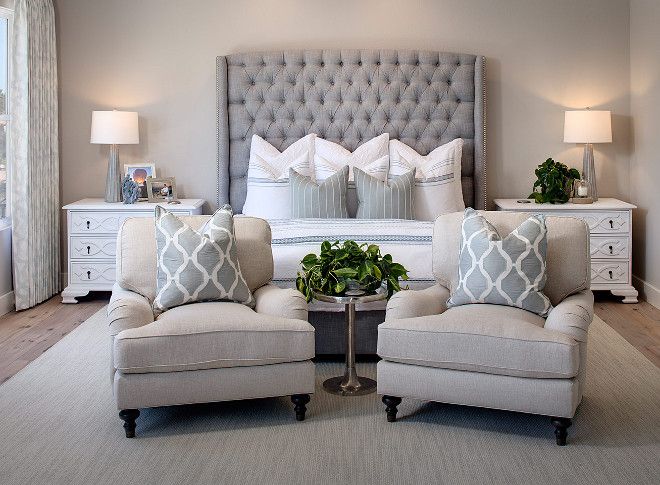 a bedroom with two chairs and a bed in the middle, one chair is upholstered