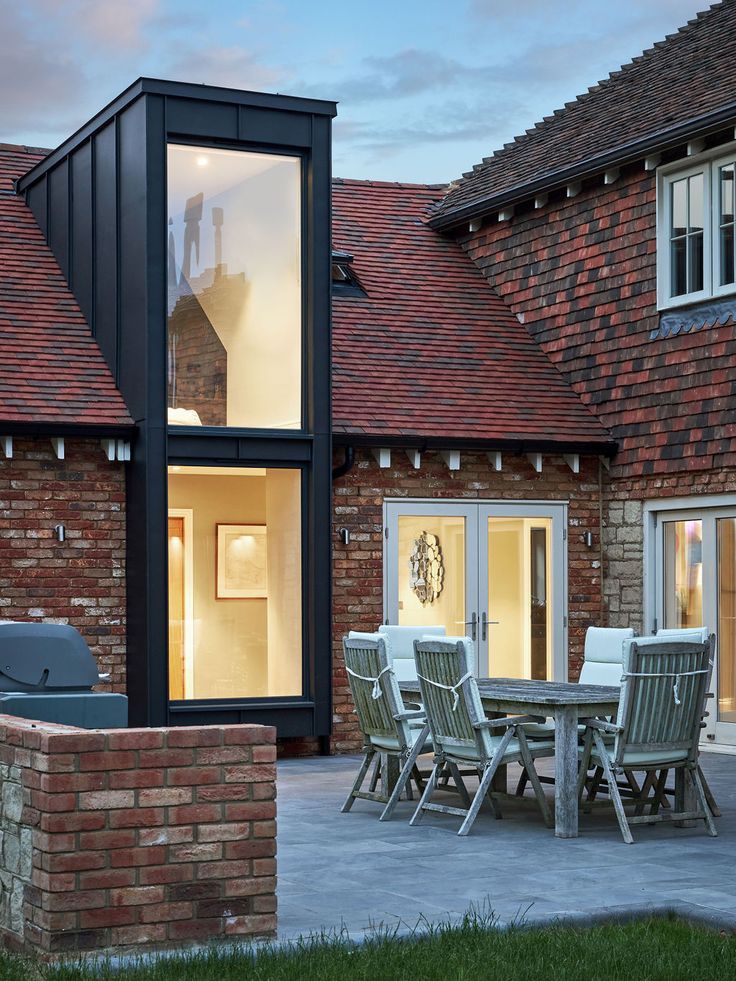 an outdoor dining table and chairs in front of a brick building with large sliding glass doors