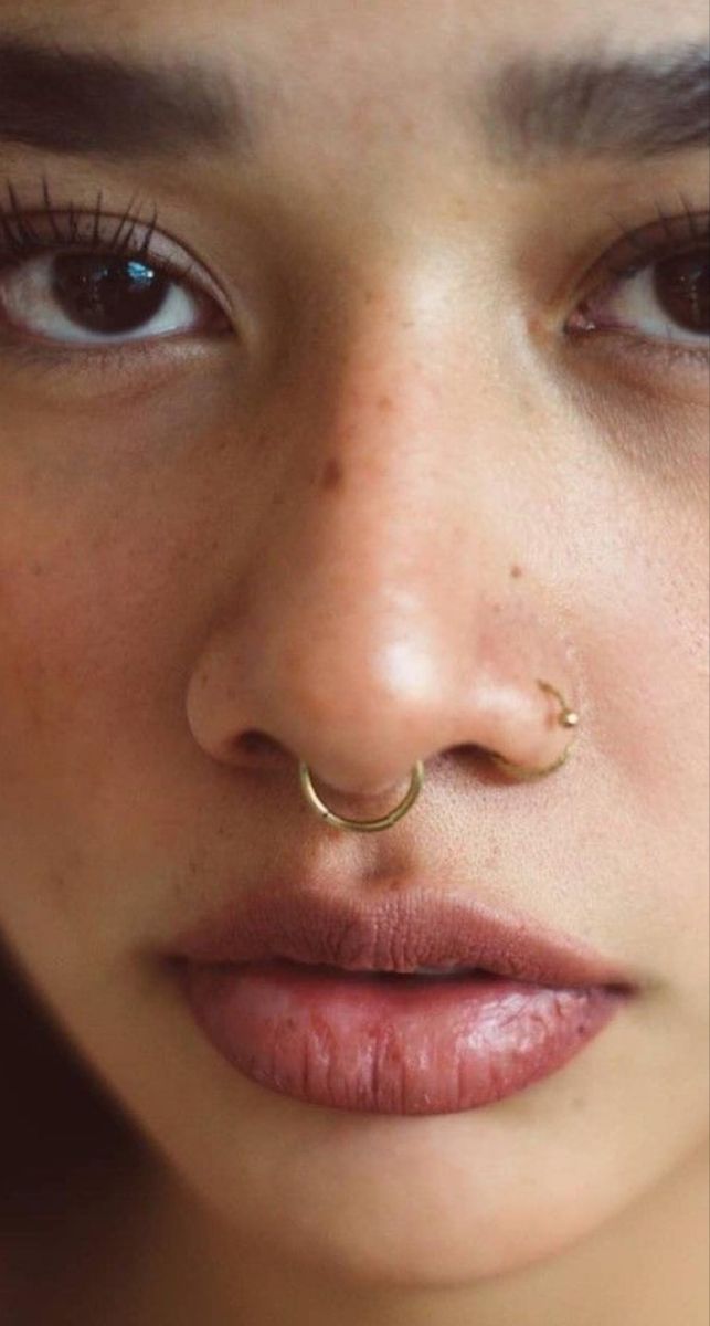 a close up of a person with a nose ring on her nose and piercing in the middle