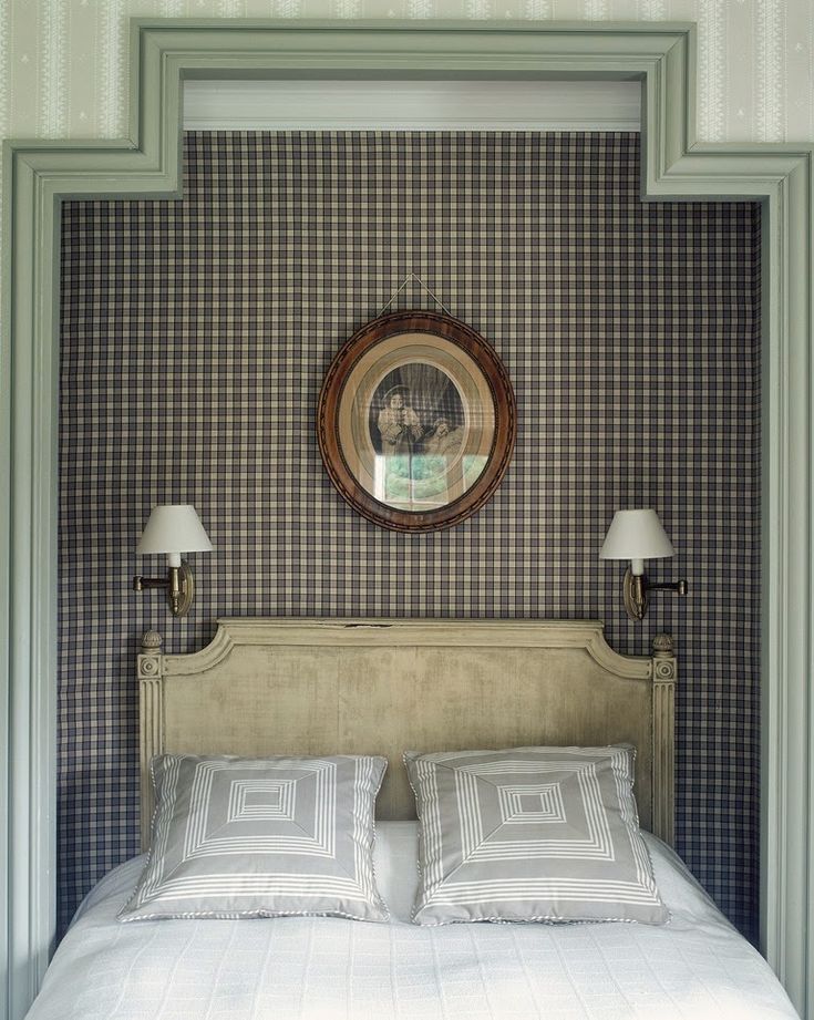 a bed with two lamps on either side of it and a mirror above the headboard