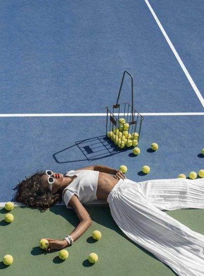 a woman laying on the ground with tennis balls