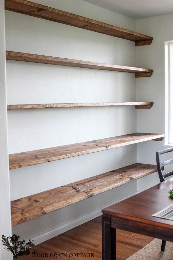 an empty room with wooden shelves on the wall and a table in front of it