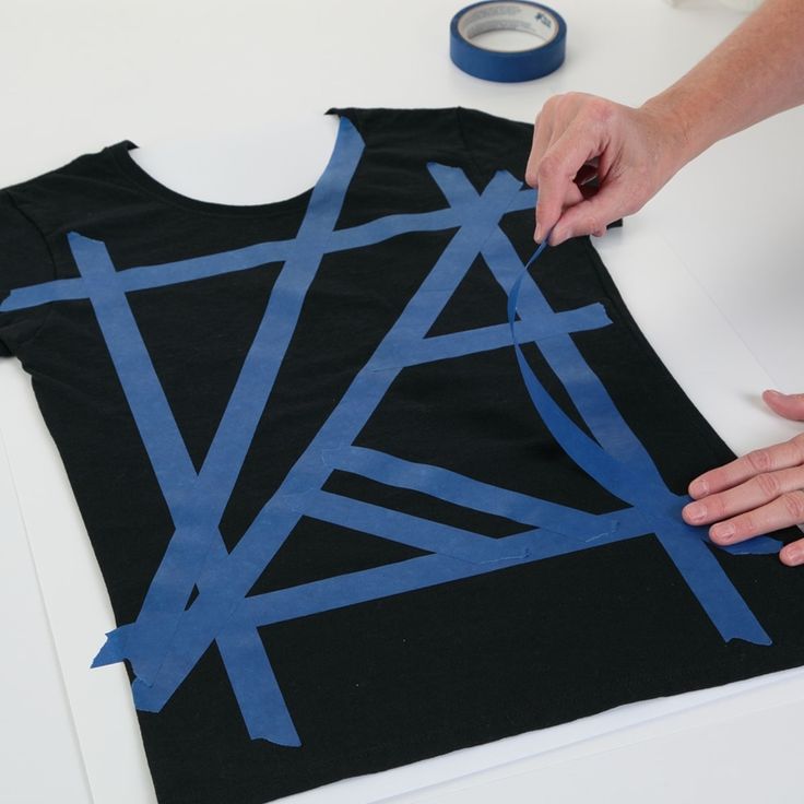 someone cutting out blue tape on top of a black t - shirt