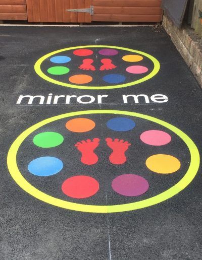 two circles painted on the ground with different colors and shapes in them, next to a garage door that says mirror me