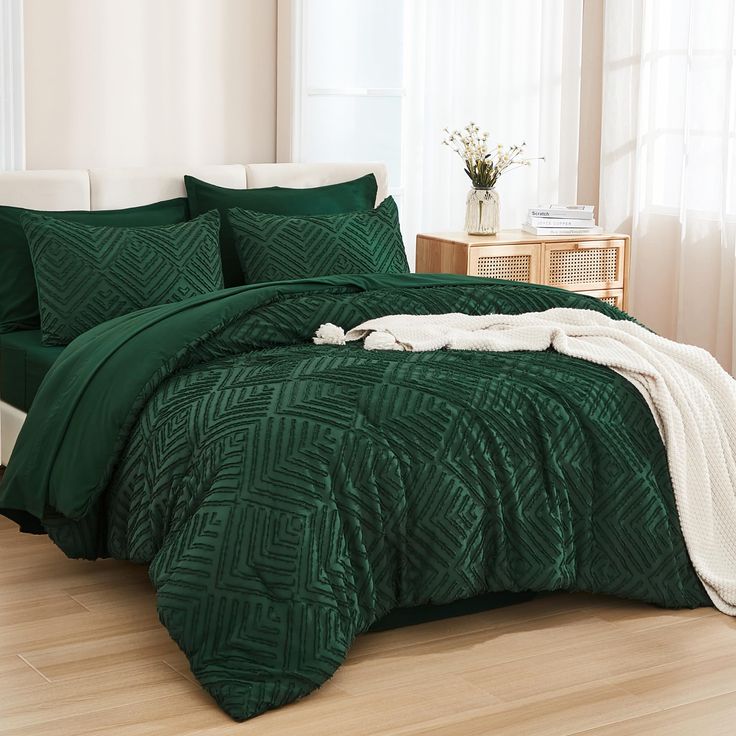 a bed with green comforter and pillows in a room