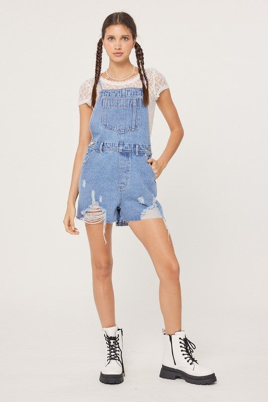 Distressed Overall Denim Romper. - Front, Back & Side Pockets -Adjustable Cross Back Drawstrings - Side Button Detail - Distressed hem Runs small, size up one. Model is wearing a small (32” bust, 26” waist, 35” hips, 5’2”) Casual Distressed Shortalls For Spring, Spring Medium Wash Shortalls With Frayed Hem, Casual Medium Wash Distressed Shortalls, Spring Cutoff Denim Shortalls, Casual Distressed Shortalls, Trendy Denim Shortalls With Frayed Hem, Spring Distressed Cotton Shortalls, Spring Distressed Medium Wash Shortalls, Summer Distressed Denim Shortalls