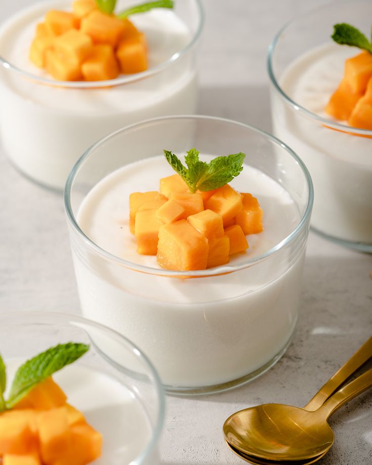 four small bowls filled with yogurt and pieces of fruit on top of each other