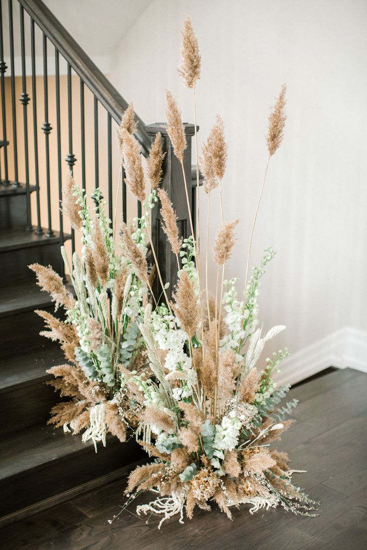 a vase filled with flowers sitting on top of a wooden floor next to a stair case