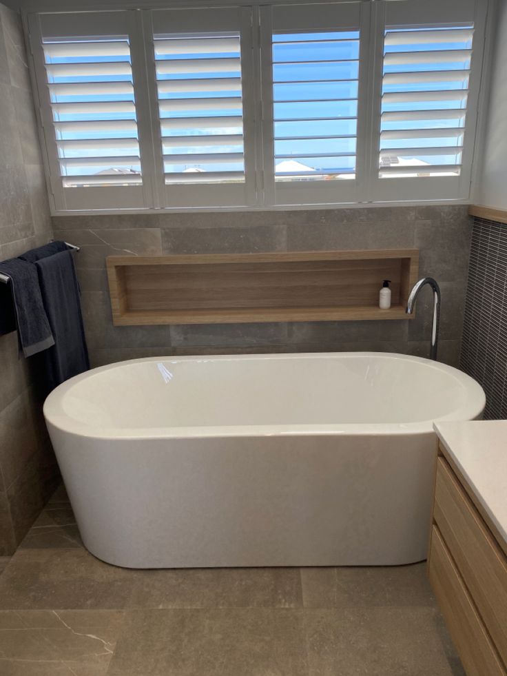 a large white bath tub sitting next to a window