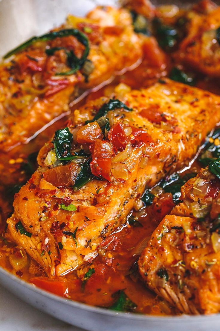 a pan filled with chicken covered in sauce and toppings on top of a table