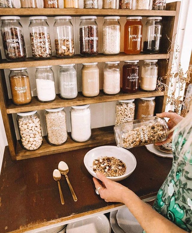 jars filled with different types of food sit on a table next to bowls and spoons