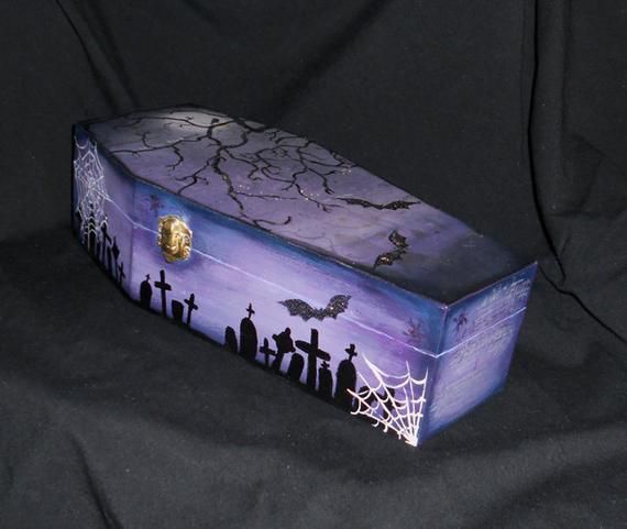 a purple and black box sitting on top of a black cloth covered surface with bats flying over it