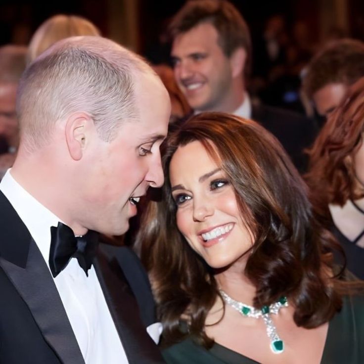 a man in a tuxedo standing next to a woman wearing a green dress