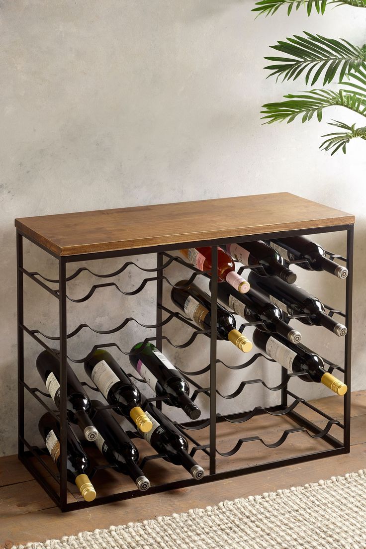 a wine rack with many bottles in it on the floor next to a plant and potted palm tree