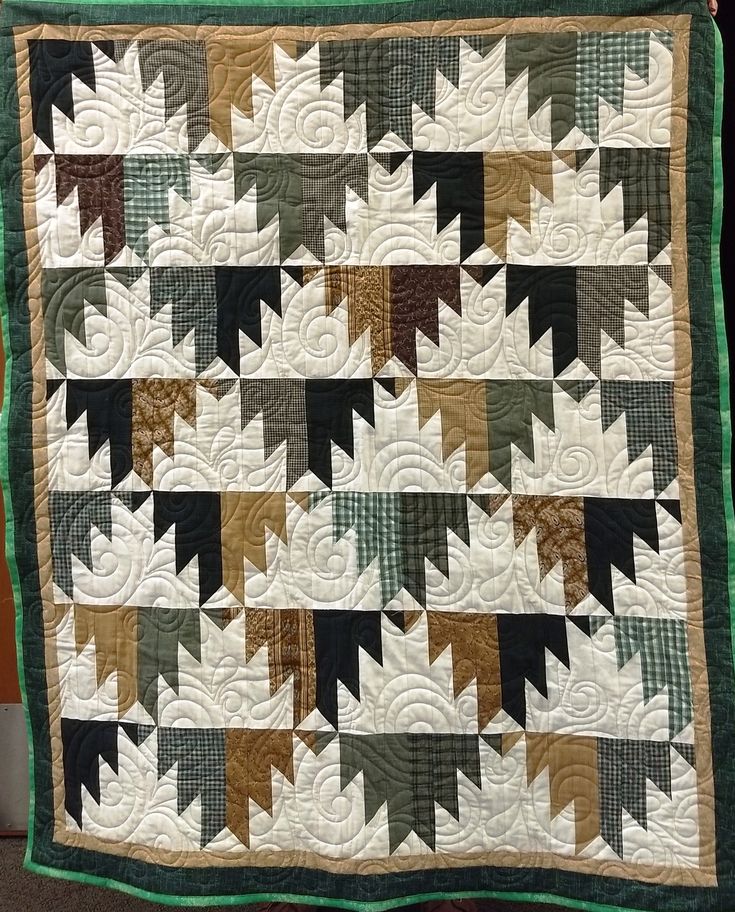 a green and white quilt is hanging on the wall