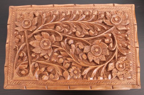 an intricately carved wooden box with flowers and leaves