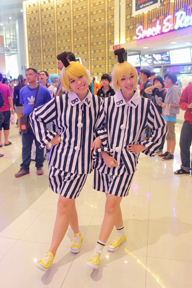 two women dressed in striped outfits posing for the camera at an indoor mall with other people