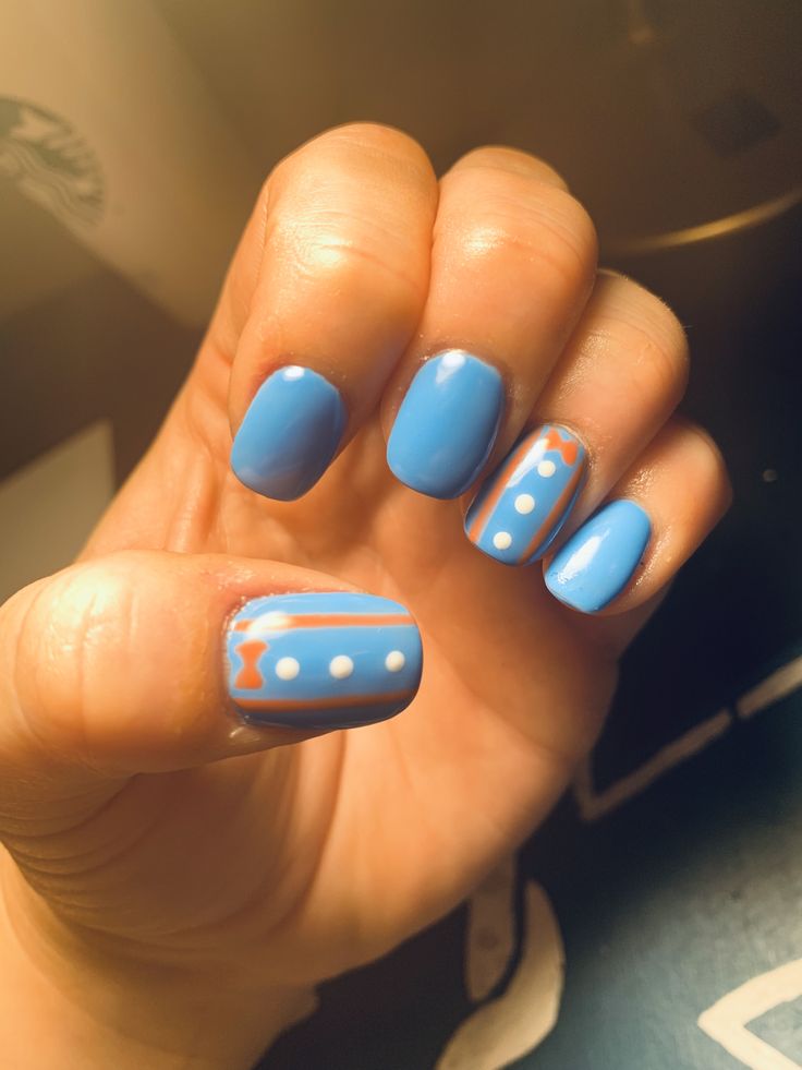 a person with blue and white nail polish holding their hand up to the camera,