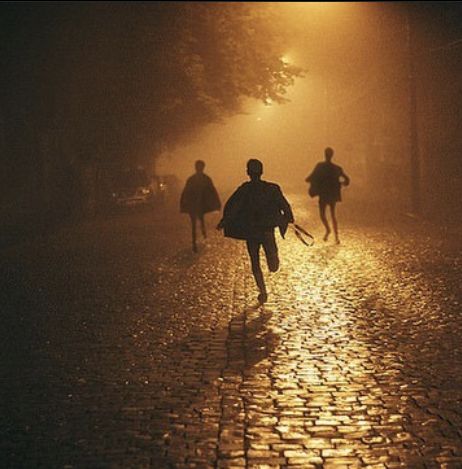 three people walking in the rain at night