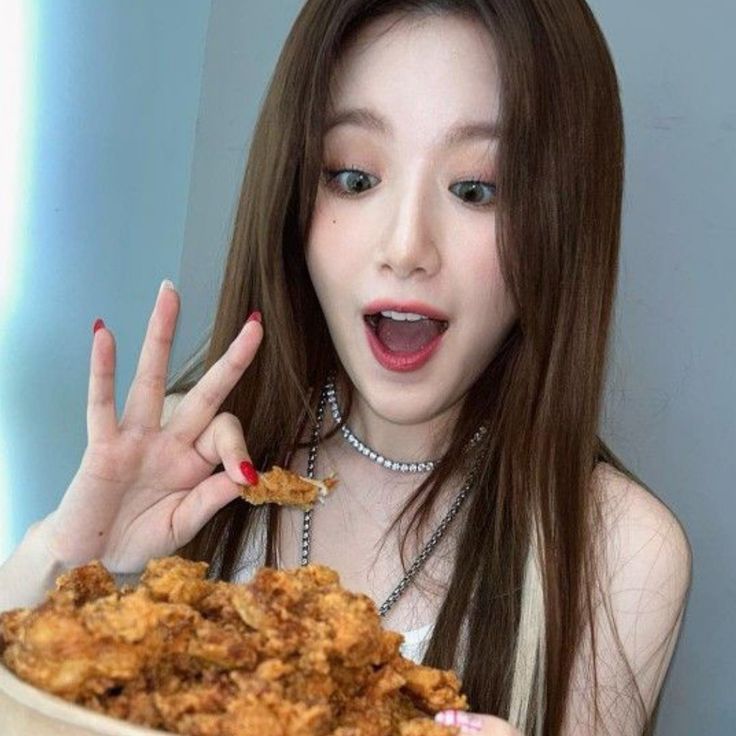 a woman with long brown hair is holding a plate of food and making the peace sign