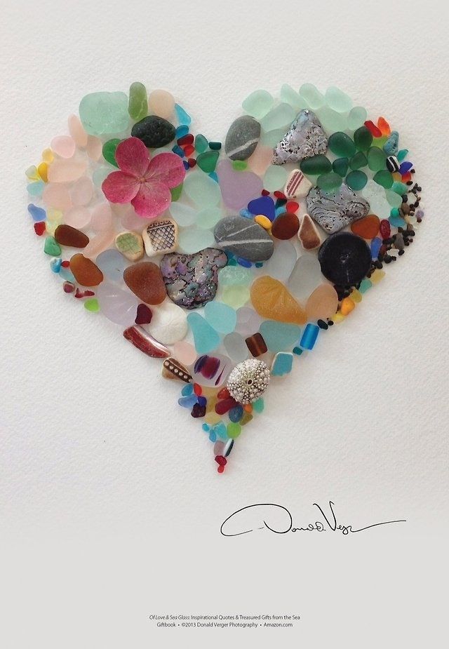 there is a heart made out of many different colored glass beads on the white wall